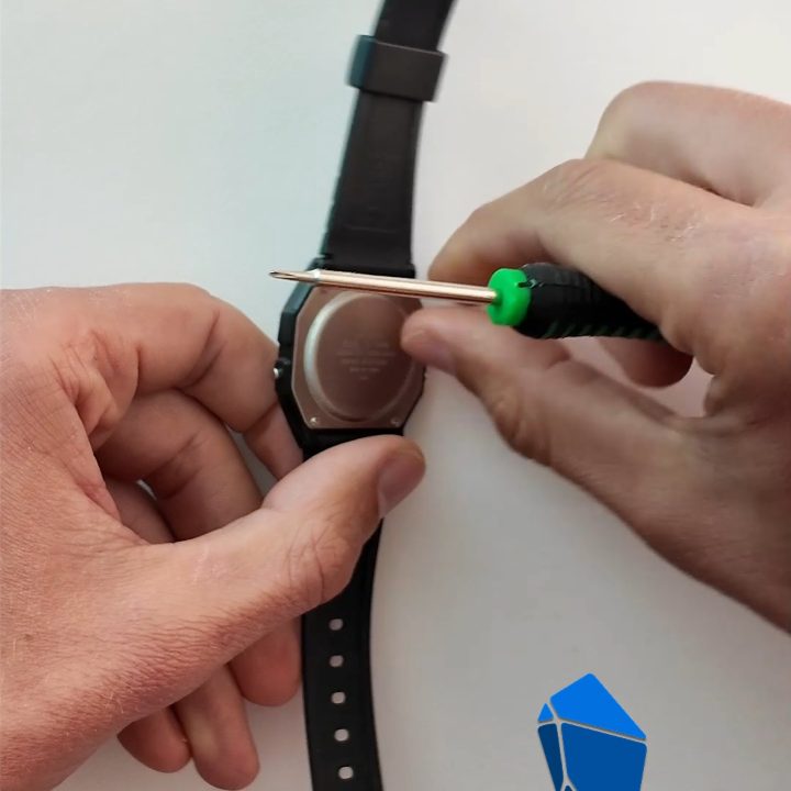 A screwdriver on one of the four screws of the watch's back.