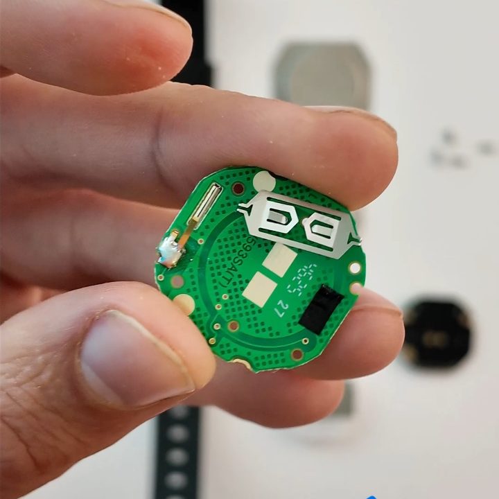 The back of the original board, with a small metal contact blade being lifted off.