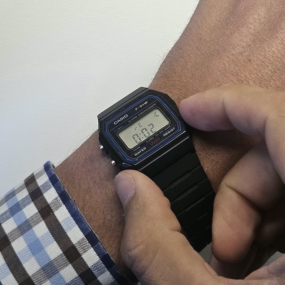 A digital watch fitted with Cobalt, on a wrist. A finger holds the button, the display shows “rEC” and the counter 0:02.